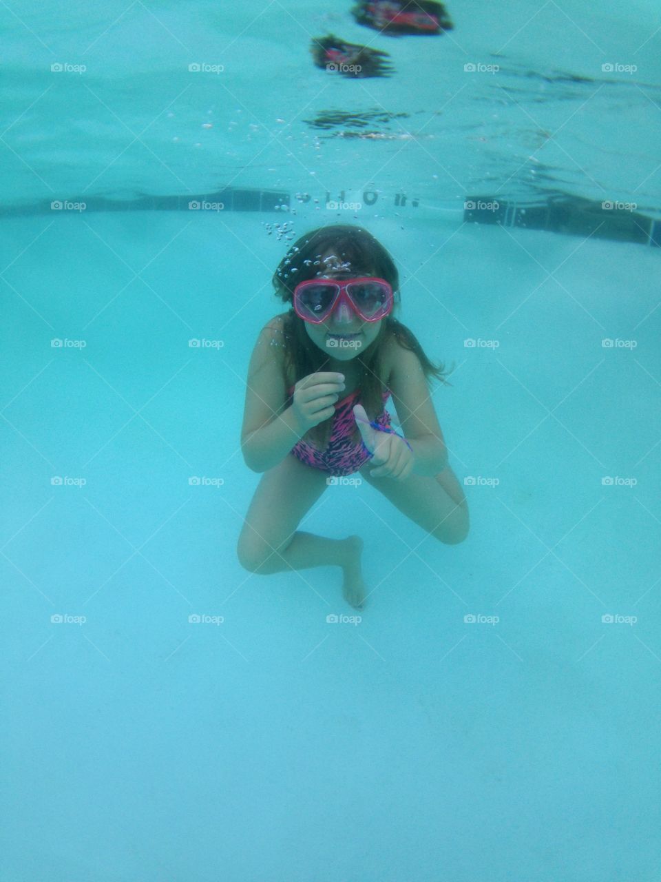 Thumbs up for swimming. Underwater view of girl giving a thumbs up