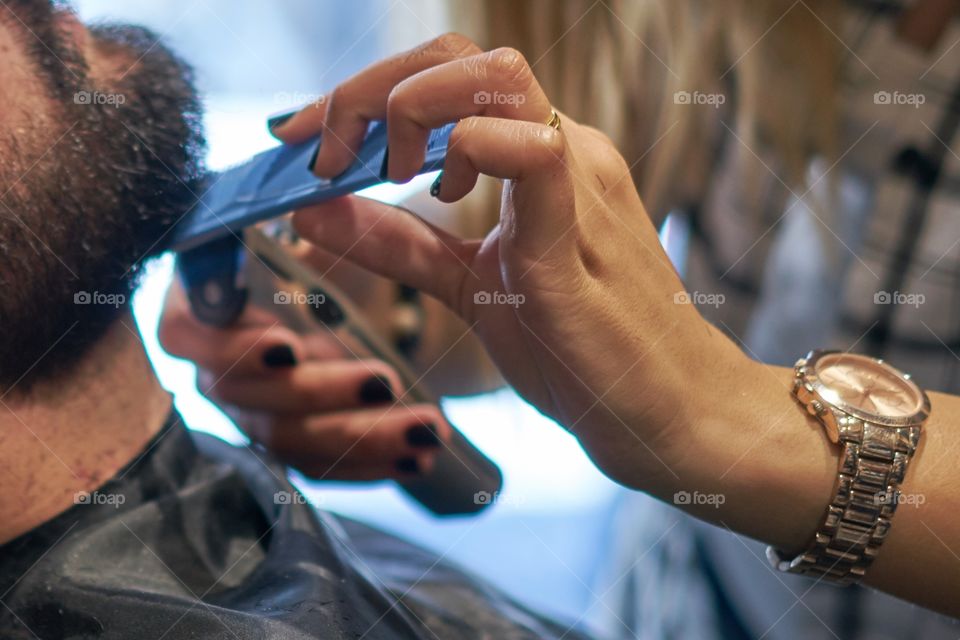 Manos de una mujer arreglando la barba de un hombre.