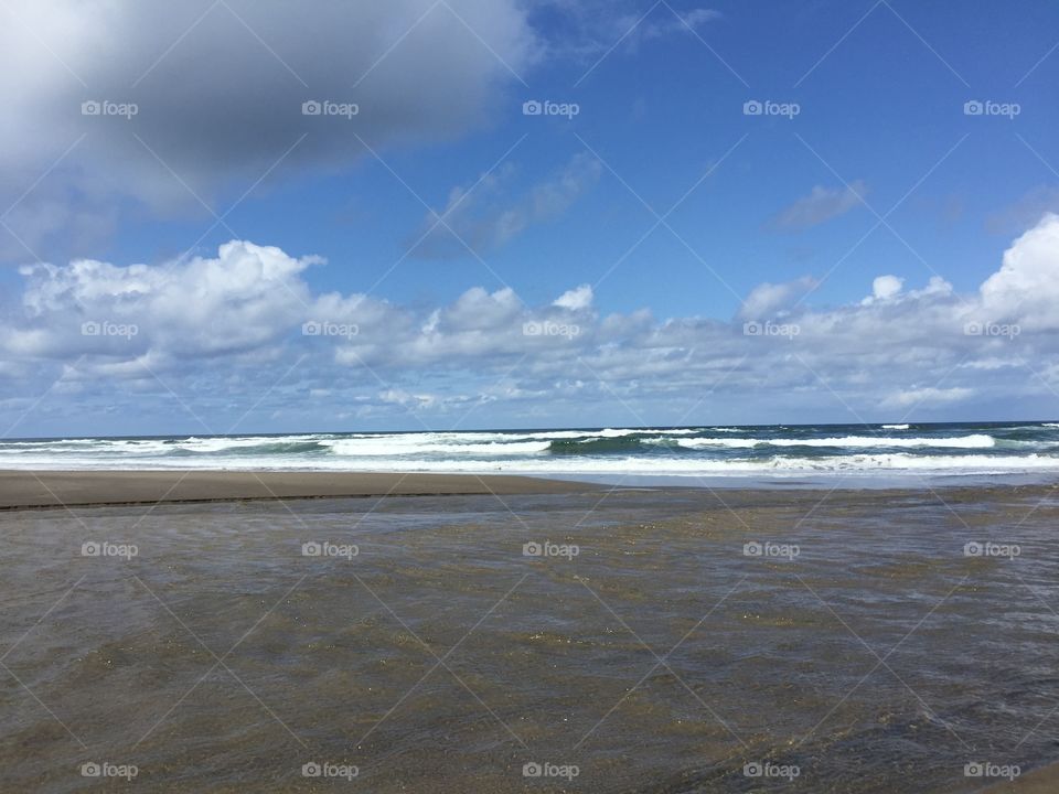 Ocean waves under blue sky and fluffy clouds