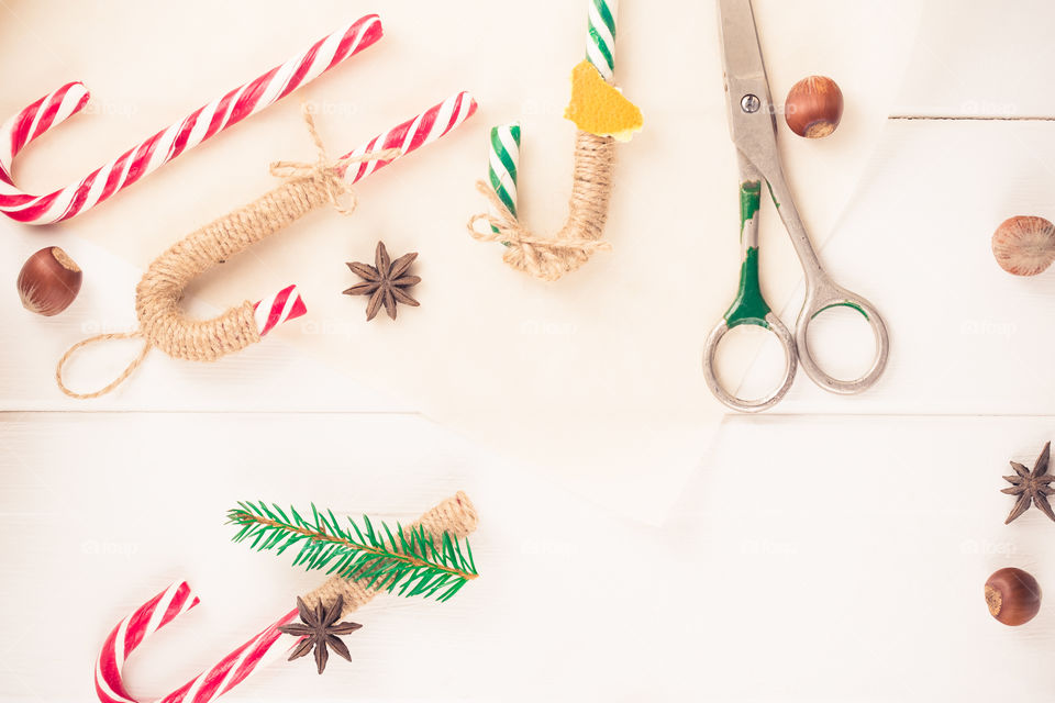 Christmas flatlay with decorated candy canes, hazelnuts, craft paper and old scissors.