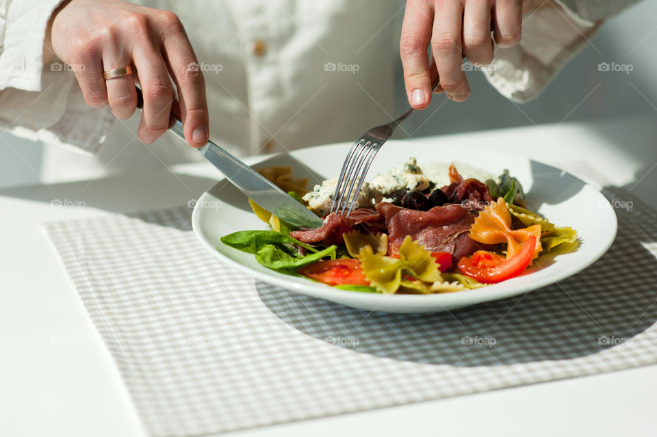 close-up of a young man eating a salad in a light kitchen