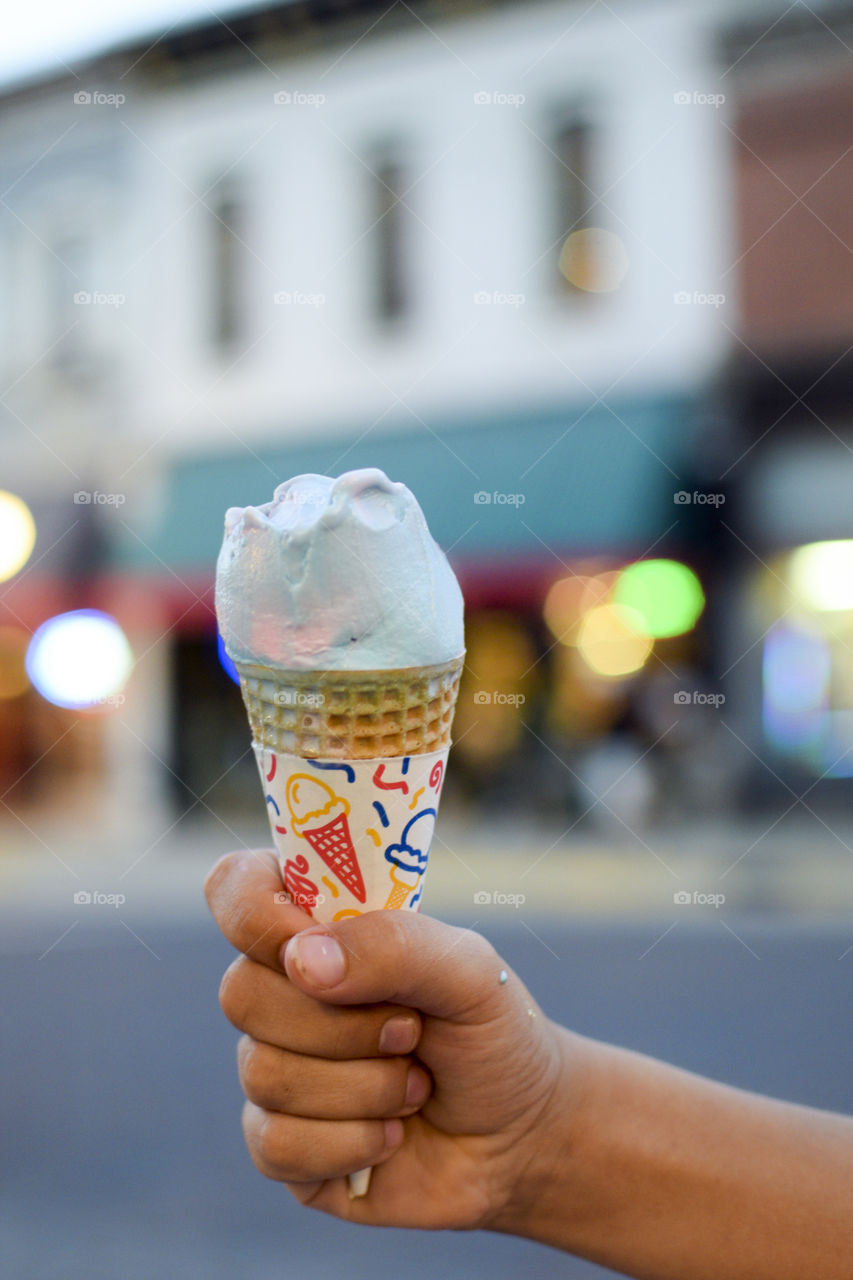 Hand holding an ice cream cone outside in the summer 
