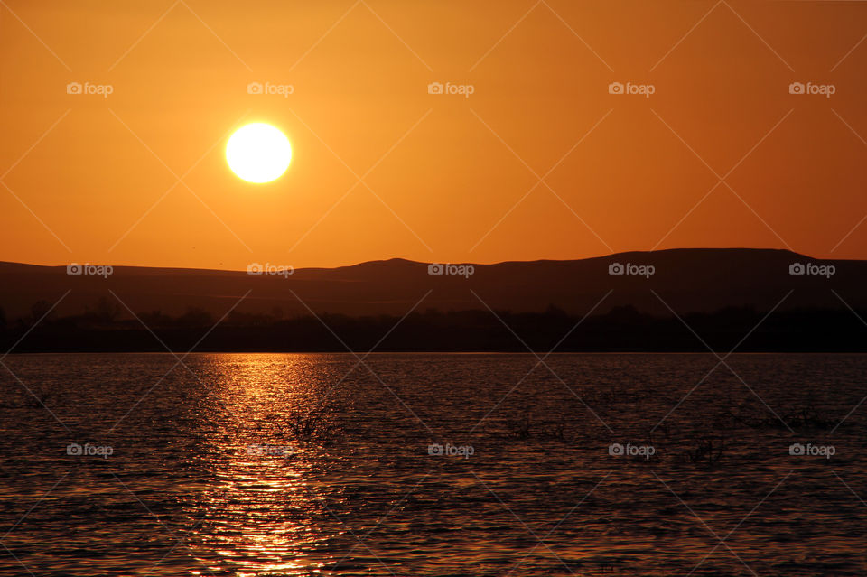 The setting sun turns the sky orange over a lake in the oasis town of Siwa, in the west of Egypt