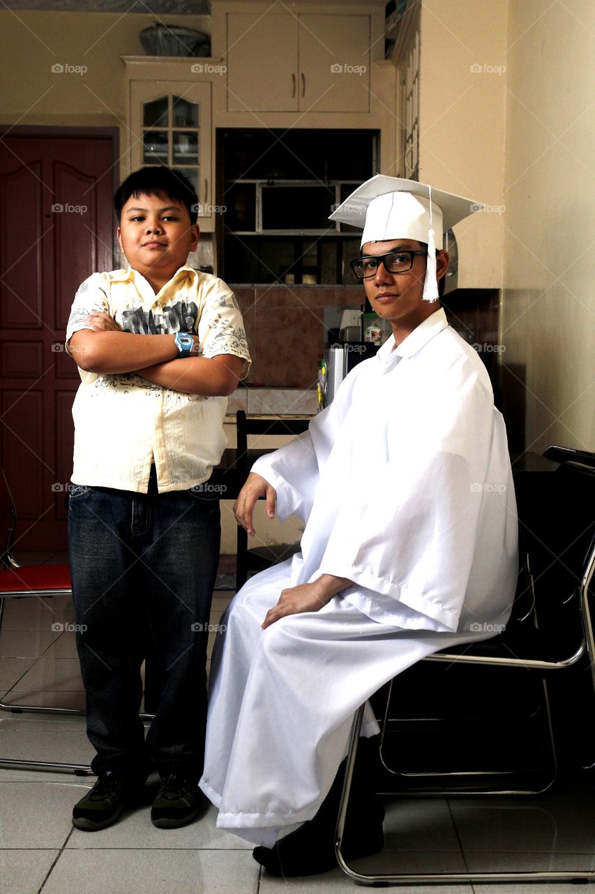 a young boy and a teen wearing graduation clothes