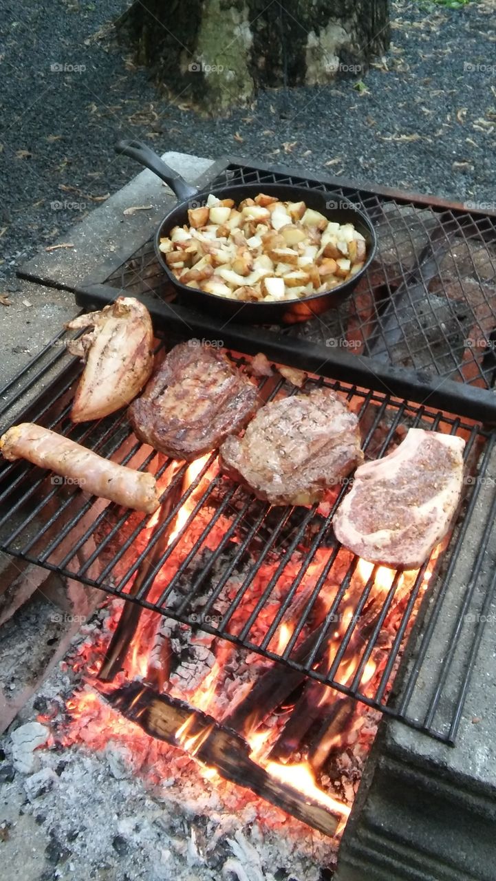 camp fire steak potatoes sausage cast iron frying pan. outside