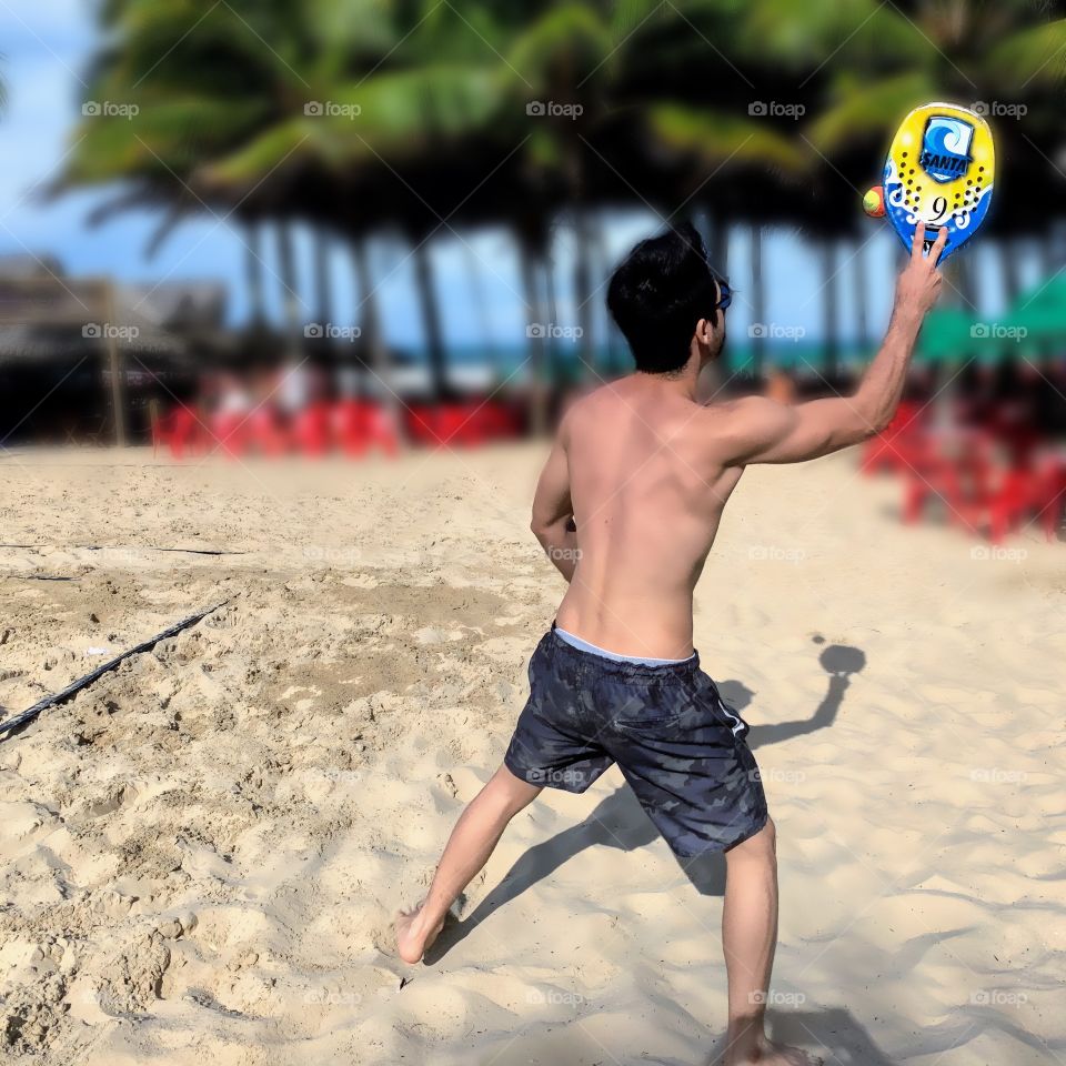 Boy playing paddleball on the beach