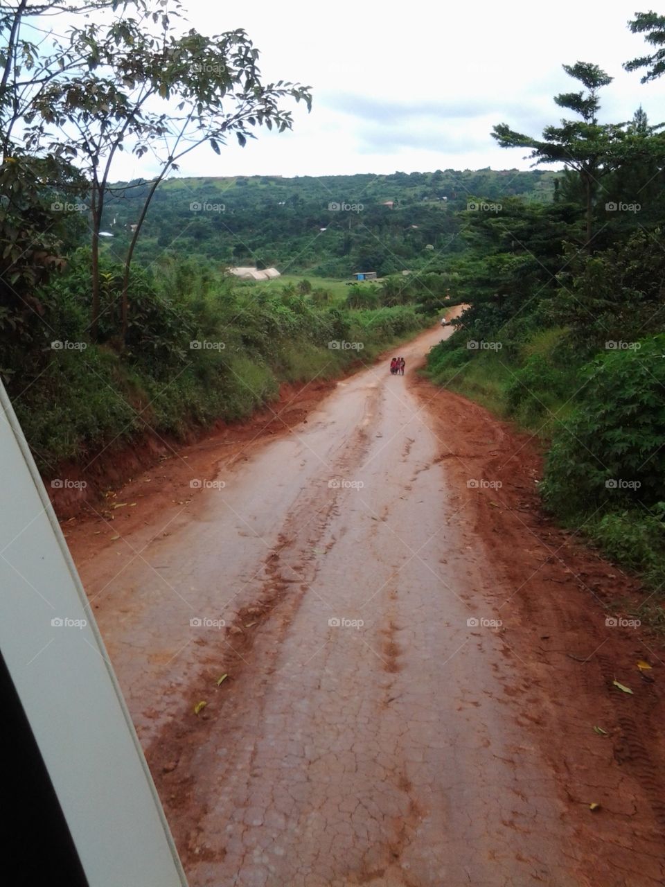 Barefoot Ugandan children chase a van down a rutted dirt road just tell mzungus goodbye