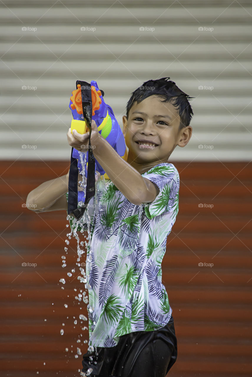 Asian boy holding a water gun play Songkran festival or Thai new year in Thailand.