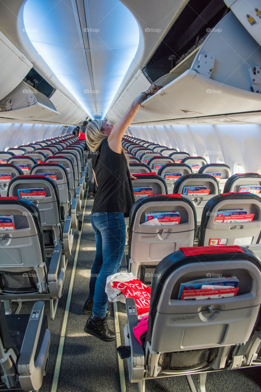 Woman trying to put suitcase in a airplane.