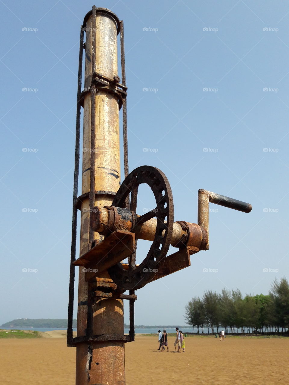 mechanical pulley rusty pillar handle on sandy beach natural walking people