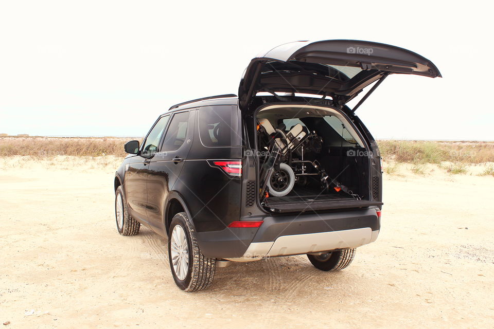 2017 land rover discovery suv offroading on beach sand with wheelchair in open trunk