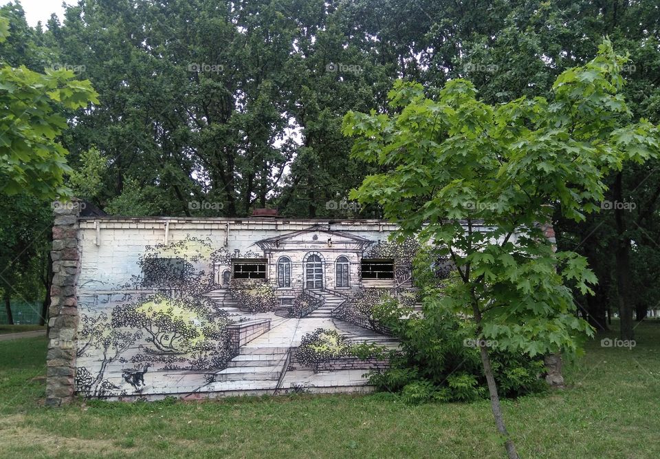 art graffiti house drawing on a wall and green trees in the park summer time