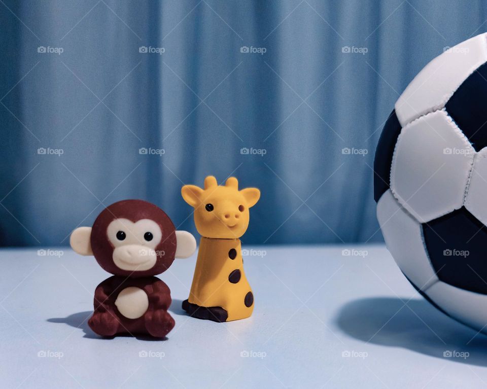 a monkey a giraffe and a soccer ball toys for children in a room close up