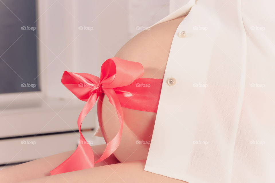 Red 
Bow on a belly of a pregnant woman