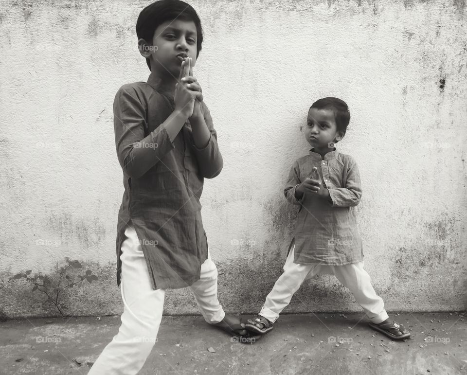 Two boys posing against wall