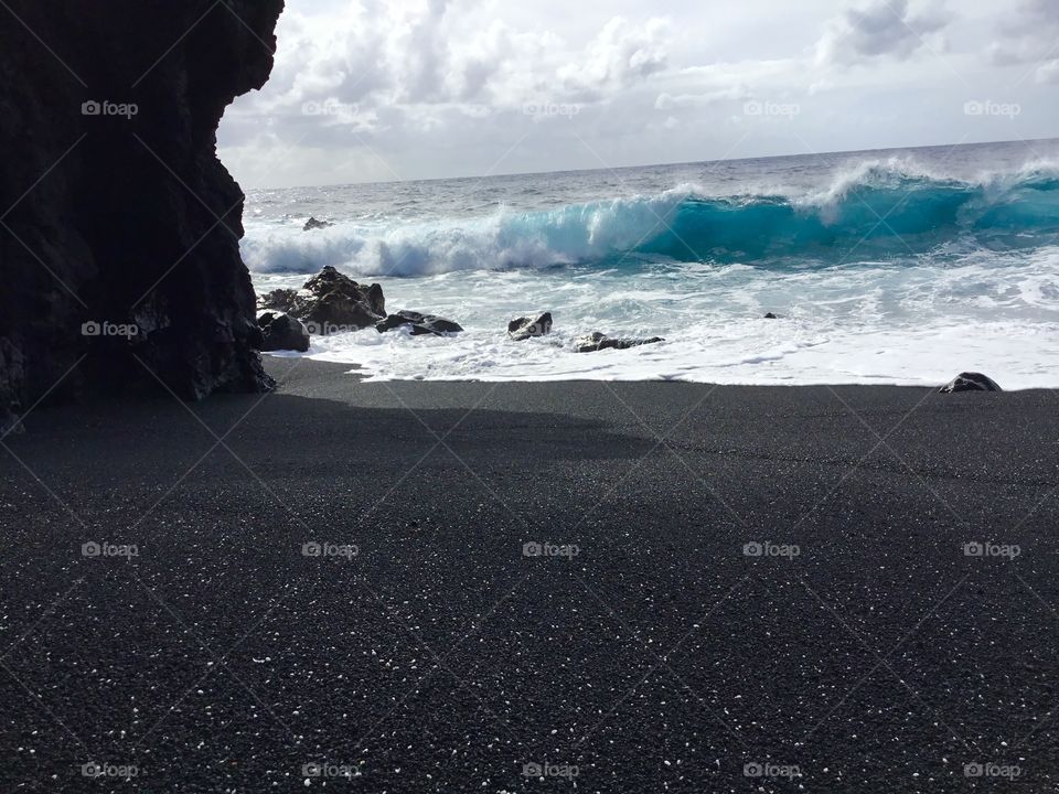 Wave meets black sand beach