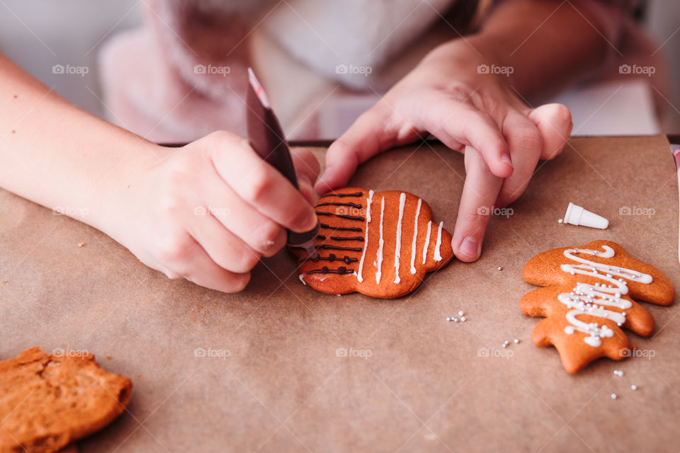 Girl decorating baked Christmas gingerbread cookies with frosting
