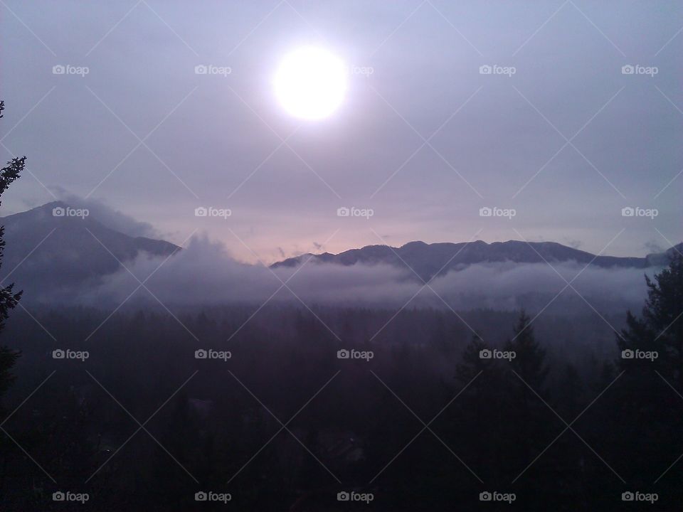 Fog And Sun. Taken from the top of Little Si in North Bend, Washington State. Fog and mist covering mountains and sun.