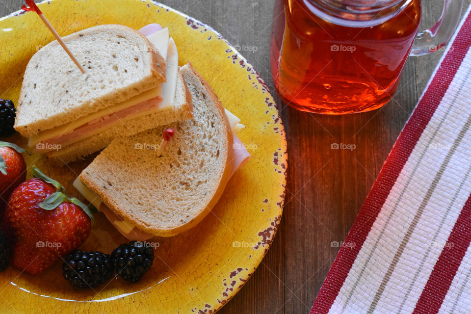 Ham and cheese sandwich with fruit and a glass of juice