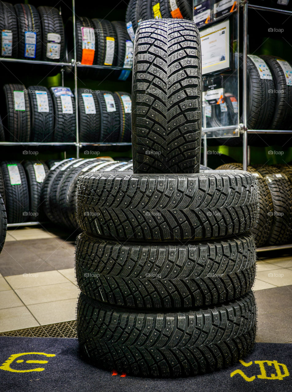 set of new winter tires with studs, tire shop in the background