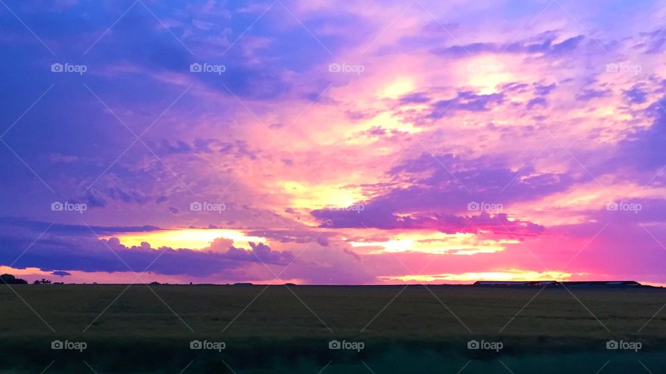 Sunset cloudy sky over hay field 