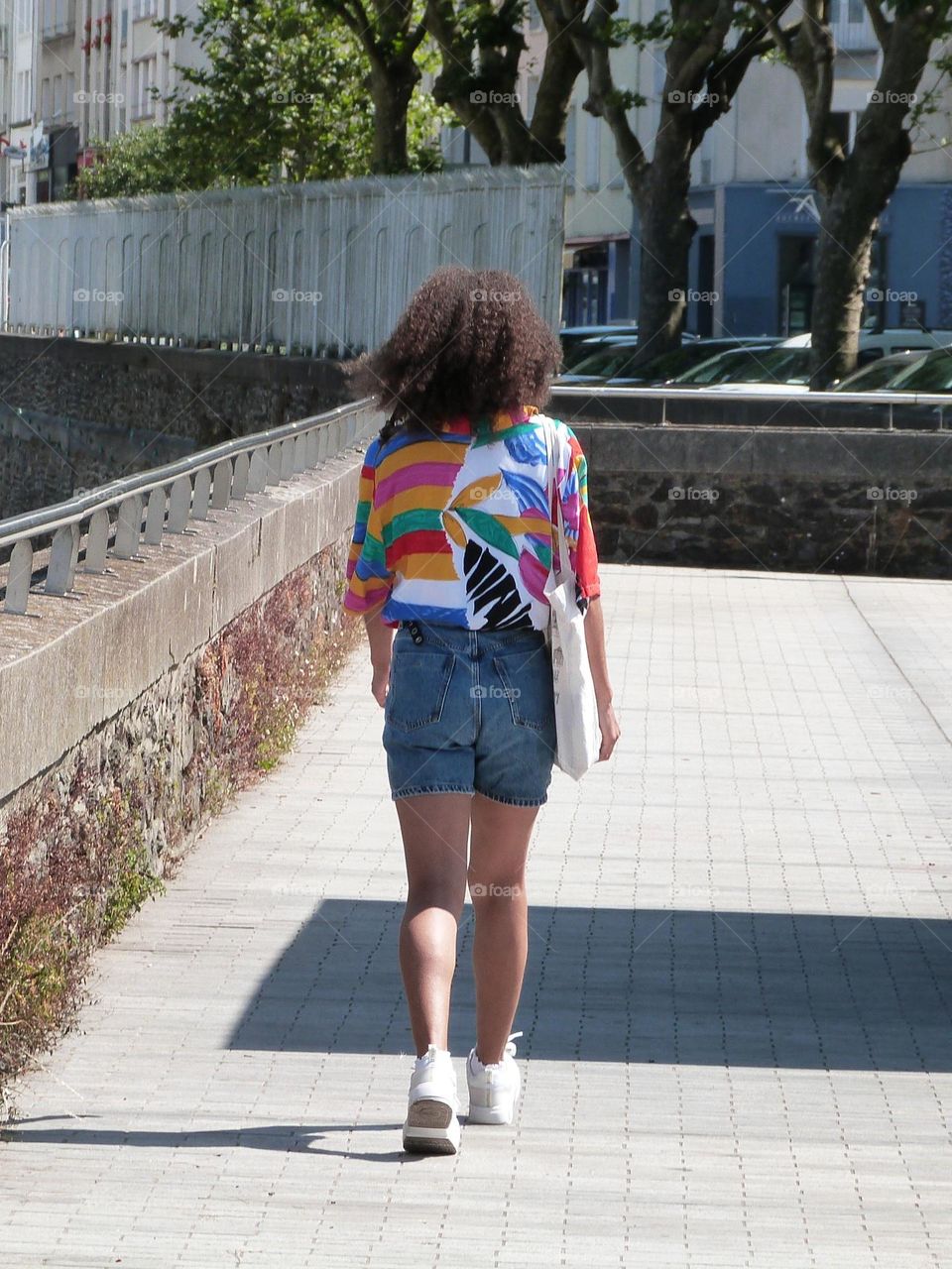 a young woman in the street wearing a blouse in the colors of the LGBTQ+ community on Pride Day