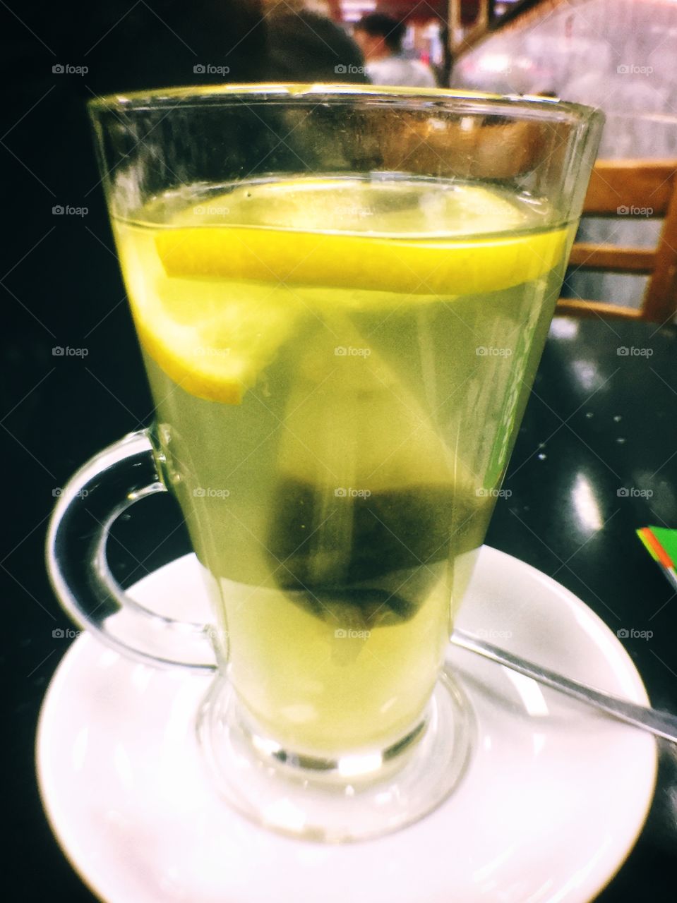 Long tall glass of lemon & ginger herbal tea in cafe 