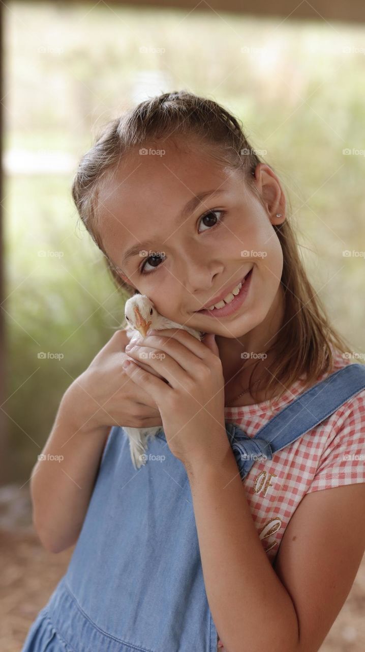 Beautiful girl hugging a baby chicken.