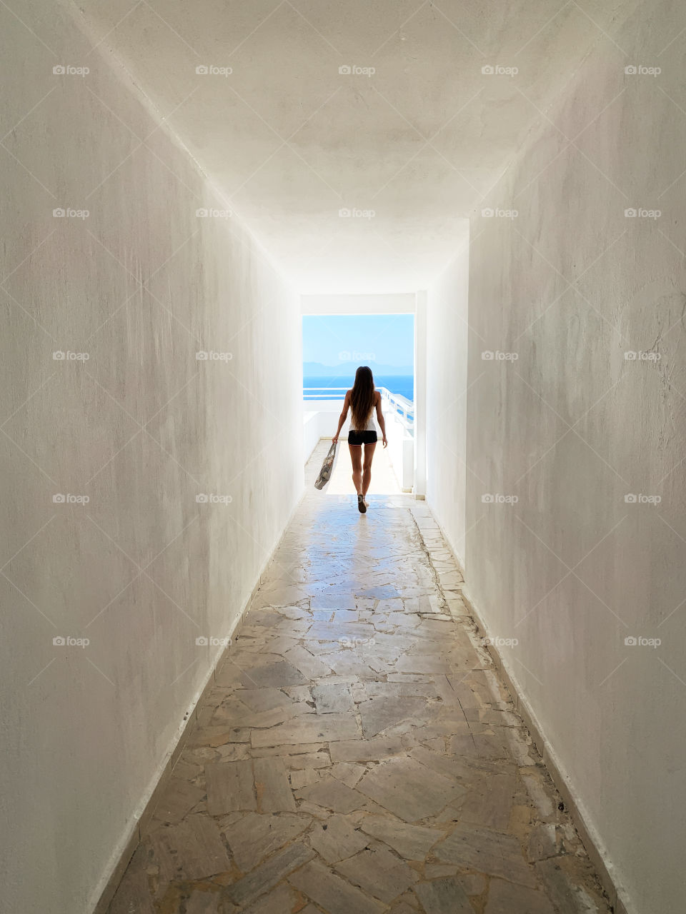 Young woman walking by the white corridor 