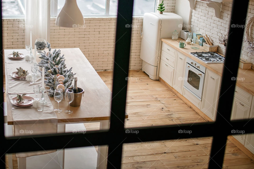 Festive winter cozy kitchen interior with garlands, decorations and gifts.  Christmas dinner at the decorated table.