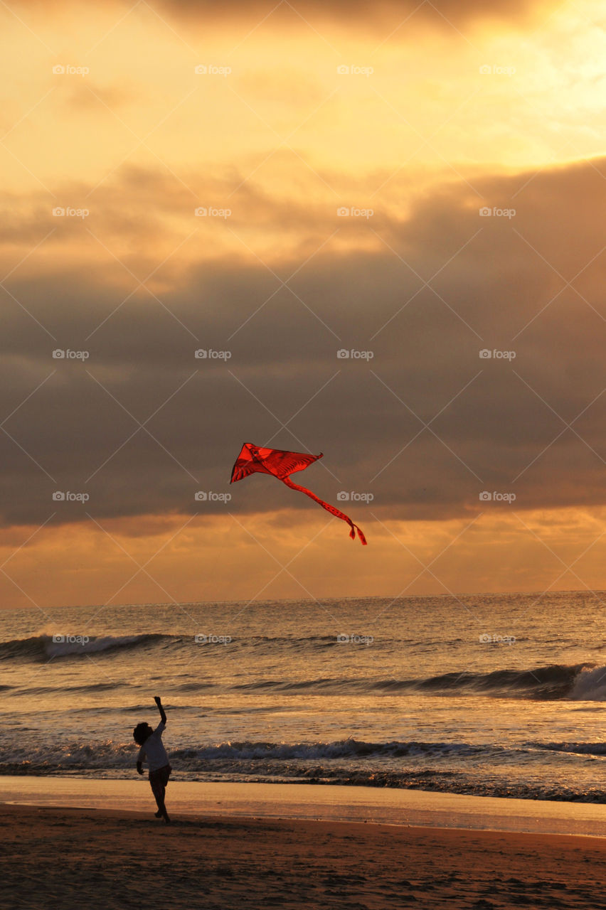 Kid playing with a kite at sunset