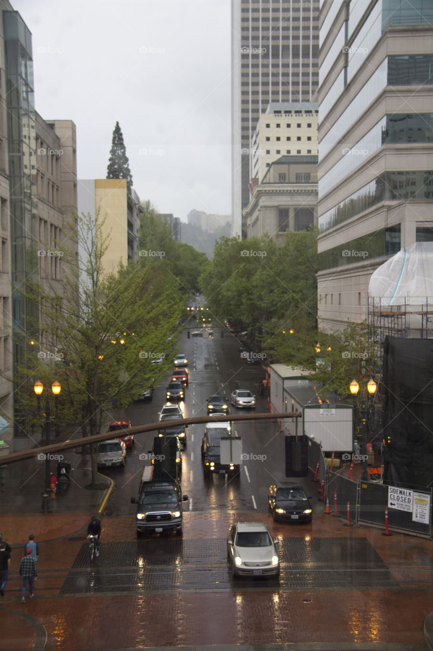 Urban Grind. Vehicles and pedestrians navigating the rainy streets of downtown Portland, Oregon.