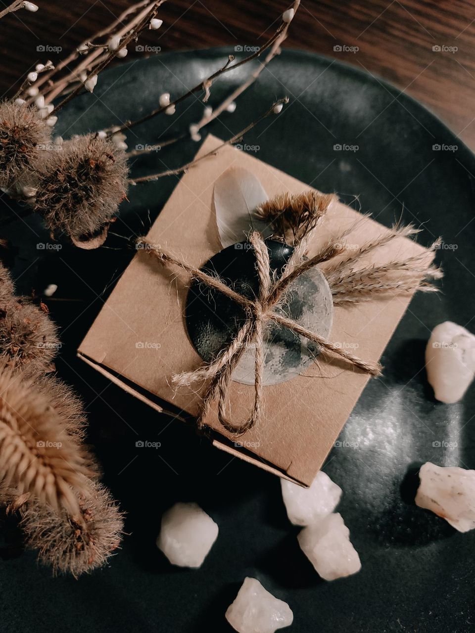 Craft paper square box decorated with feather, dried herbs and moon sticker