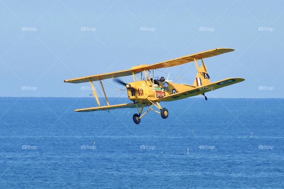 yellow small plane flying over the sea