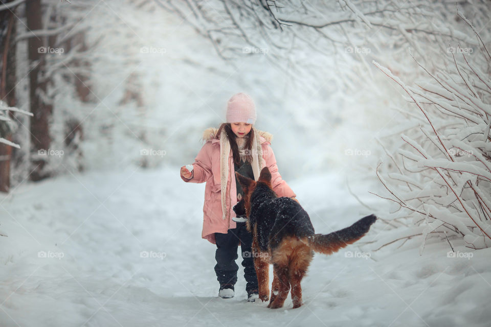 Portrait of beautiful Little girl and puppy at winter forest