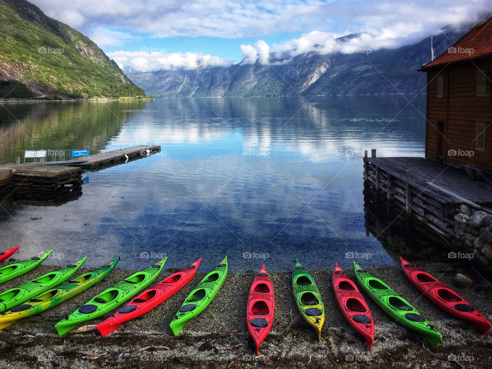 Kayaks lined up along the shore of a fjord lake in Norway