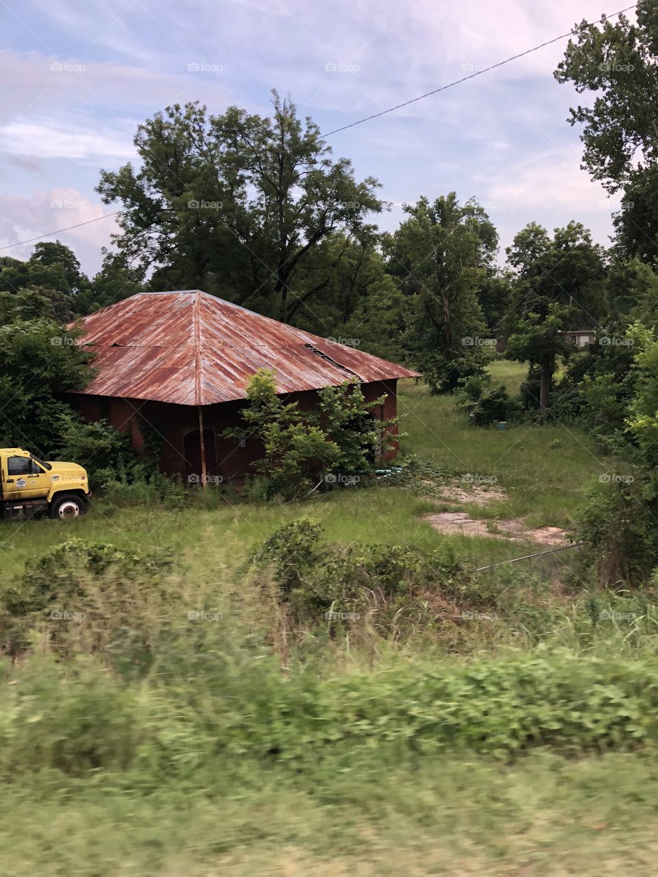 Very old building with a rusty tin roof in the south and a yellow truck. 