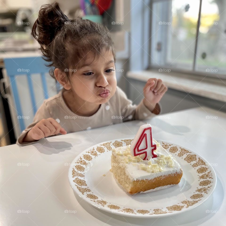 Little girl blows out birthday candles, little girl turns four years old, delicious slice of cake, birthday cake for little four year old 