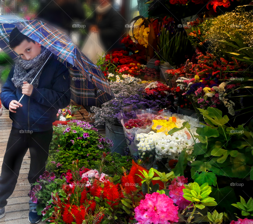Boy standing with umbrella near florist shop