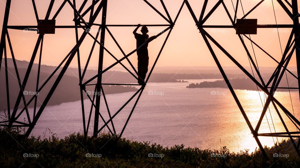 Sunset on the power lines. Silhouette of a person up on a power line tower looking at the view of Lake Whatcom