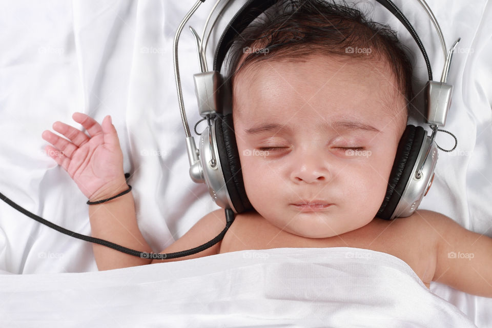 Indian baby boy with headphones listening to music