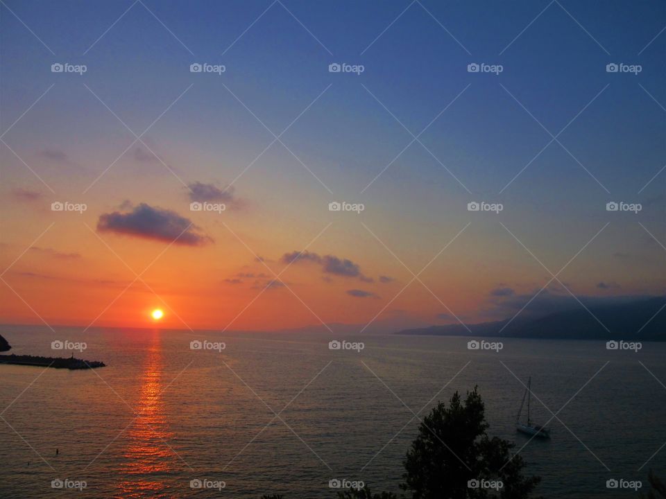 Sunset over port of Palinuro with sailboat. (Italy ).