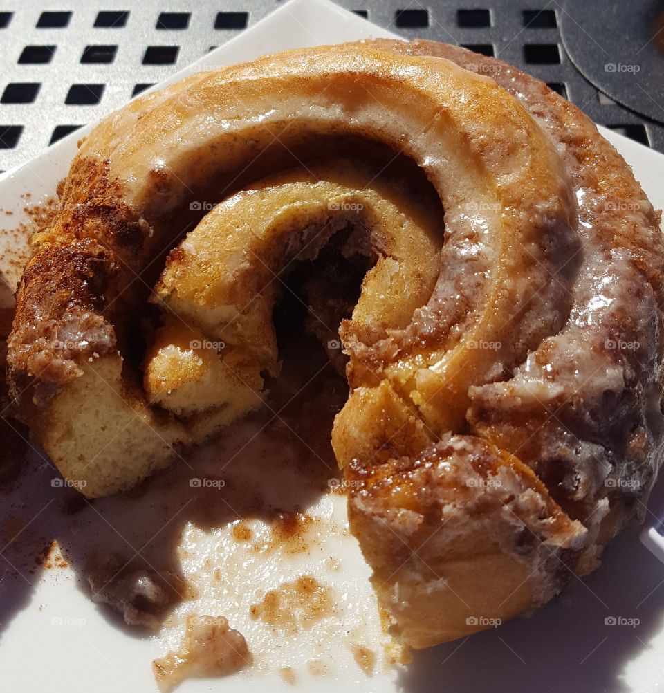 cinnamon roll at a coffee shop,  eating out on the patio during the cool summer morning with the sun shining warmly.