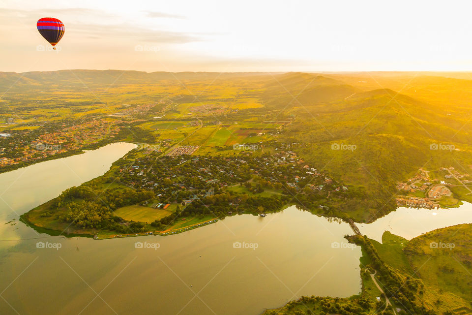 Sunrise over the mountains on a hot air balloon trip with a river and dam and village below. Beautiful air view over the valley and seeing the sunrise.