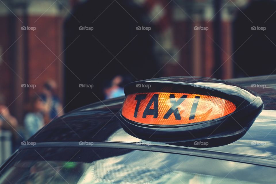 A London black cab taxi sign on top of a cab.