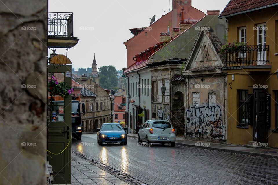 Cars are driving on a road that is wet from the rain.