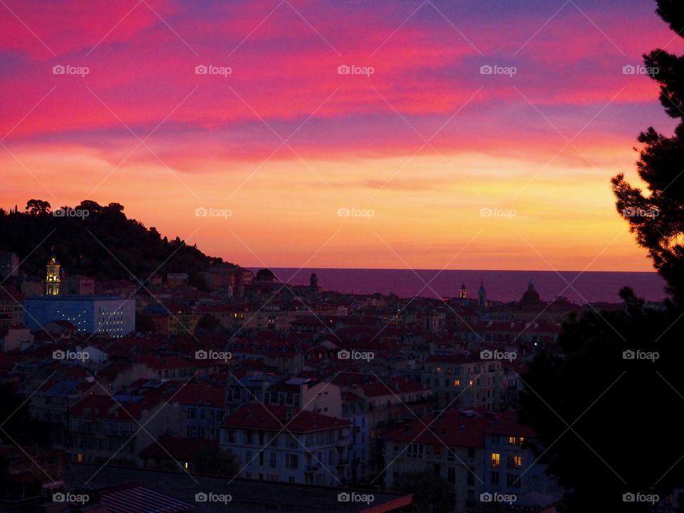 View of colorful sky at sunset overlooking the old town and sea in Nice, France.