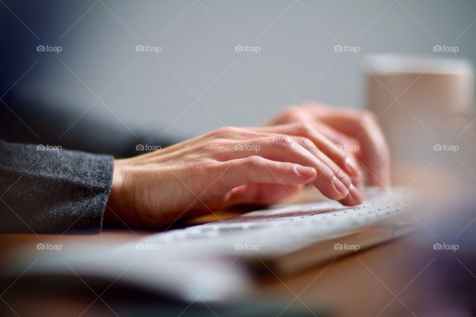 Female hands typing on a computer keyboard working in her office.