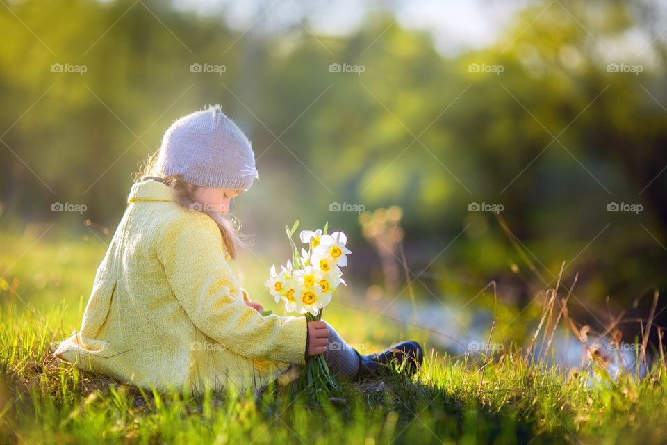 Little girl with narcissus bouquet in spring park