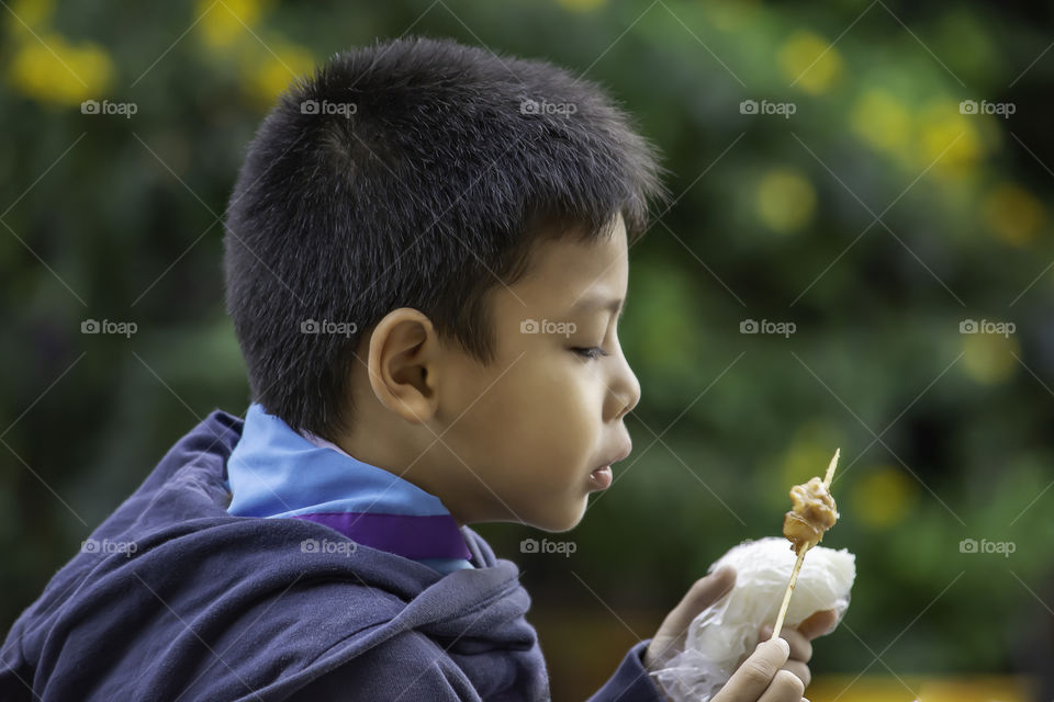 Asian boys are eating sticky rice and pork roast , The food is simple and popular to eat breakfast in Thailand.